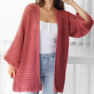 Pu&ograve; includere: Un cardigan lungo in crochet con apertura frontale, di colore rosa polvere. Il cardigan ha una vestibilit&agrave; ampia e una silhouette ampia e fluida. &Egrave; realizzato con un delicato motivo a punto aperto.