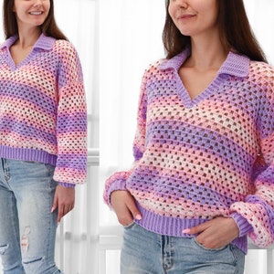 May include: A purple and pink striped crochet sweater with a v-neck and a collar. The sweater has a loose fit and long sleeves.