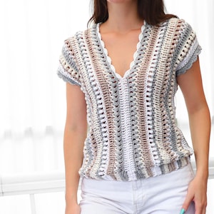 Puede incluir: Top de crochet de manga corta en una paleta de colores neutros de blanco, gris y marr&oacute;n. El top presenta un escote en V con un borde festoneado y una cintura ligeramente fruncida. El patr&oacute;n de crochet crea un dise&ntilde;o texturizado y abierto.
