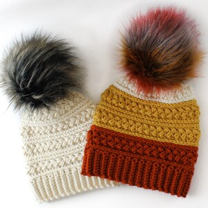 Puede incluir: Dos gorros de punto con pompones de piel sint&eacute;tica. Un gorro es crema con un pomp&oacute;n negro, el otro es multicolor con un pomp&oacute;n marr&oacute;n y rojo.