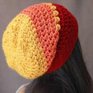 May include: A crocheted beanie hat with a yellow, orange, and red color gradient. The hat is made with a single crochet stitch.