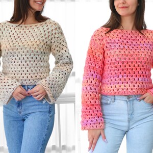 May include: Two crochet sweaters, one in cream and the other in shades of pink and orange. Both sweaters have a loose, open weave design with long, flared sleeves and a boat neck. The sweaters are paired with blue jeans.