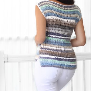 May include: A striped crochet top with a scoop neck and sleeveless design. The top is made with a variety of colors, including blue, green, brown, and white.