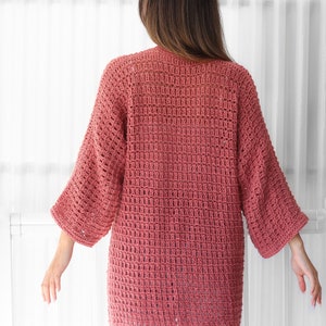 Pu&ograve; includere: Un cardigan rosa lavorato a uncinetto con una vestibilit&agrave; ampia e maniche a 3/4.