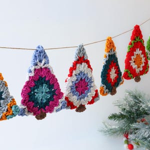 Puede incluir: Una guirnalda de &aacute;rbol de Navidad de crochet colorida con acentos rojos, verdes, azules, blancos y naranjas. La guirlande est&aacute; enhebrada en una cuerda de hilo y es perfecta para decorar un hogar para las fiestas.