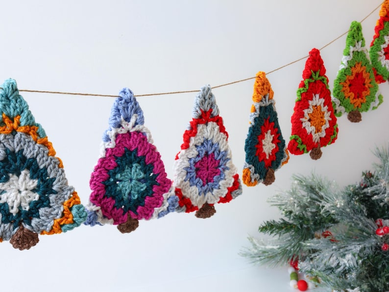 Puede incluir: Una guirnalda de &aacute;rbol de Navidad de crochet colorida con acentos rojos, verdes, azules, blancos y naranjas. La guirlande est&aacute; enhebrada en una cuerda de hilo y es perfecta para decorar un hogar para las fiestas.