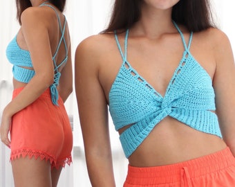 May include: A blue crochet halter top with a criss-cross back and a knotted front. The top is paired with coral coloured shorts.