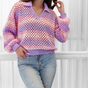 Peut inclure: Un pull en crochet ray&eacute; violet clair, rose et blanc avec un col en V et un col montant. Le pull est ample et &agrave; manches longues.