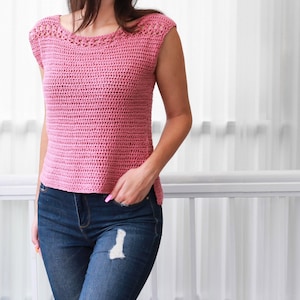 May include: A pink crochet top with a crocheted neckline and short sleeves. The top is worn with blue jeans.