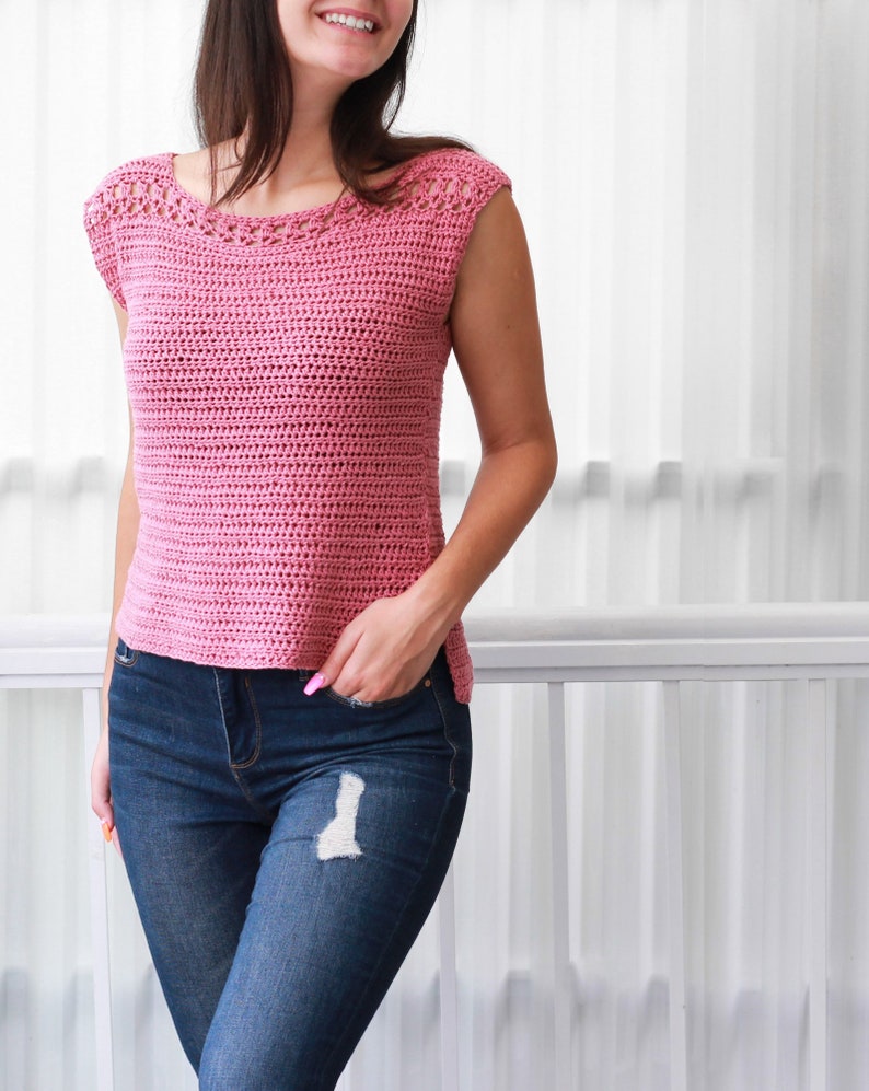 May include: A pink crochet top with a crocheted neckline and short sleeves. The top is worn with blue jeans.