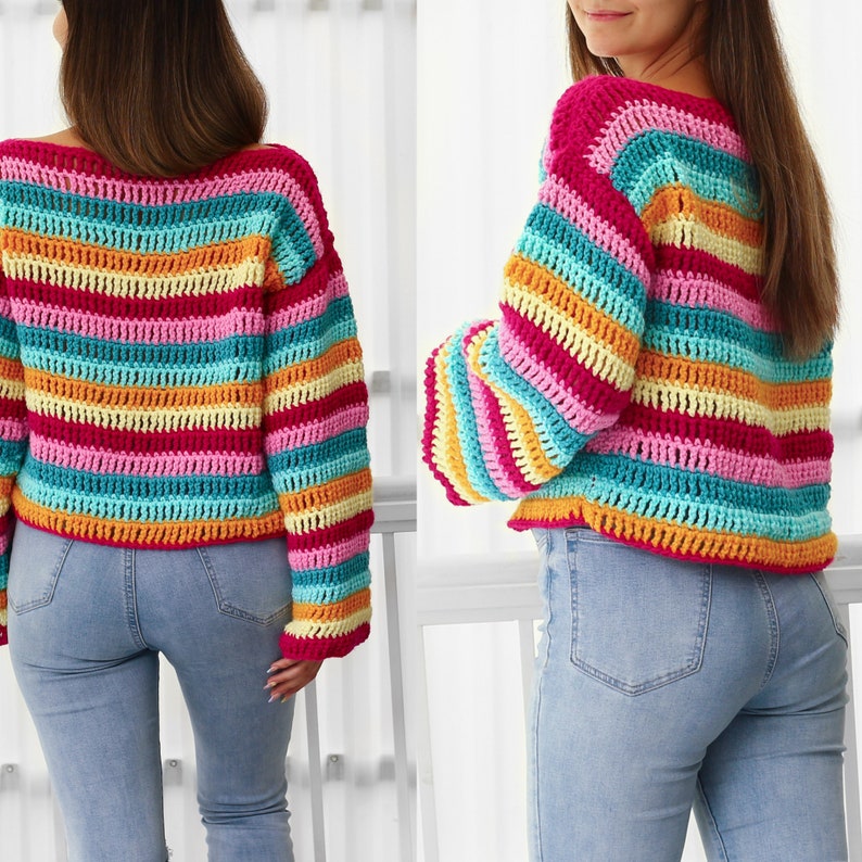 Peut inclure: Un pull en crochet ray&eacute; arc-en-ciel &agrave; manches longues. Le pull est de style court et est fait de plusieurs couleurs, dont le rose, le jaune, l'orange, le bleu et le vert.
