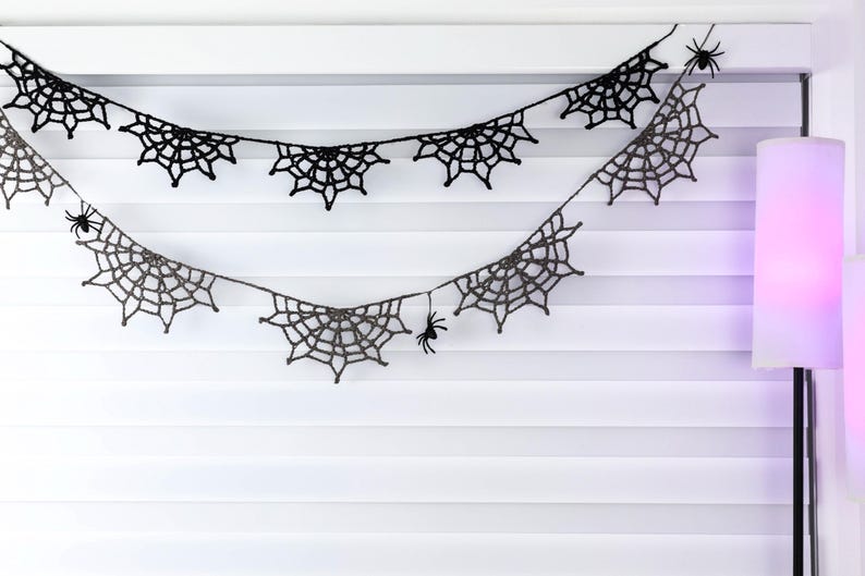 May include: A black crochet garland featuring multiple spider web motifs connected by a thin string. Small black spider figures are attached to the web patterns at various points along the length of the decorative hanging piece.