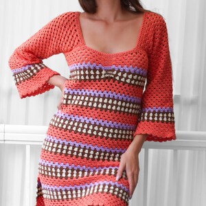May include: A crocheted dress with a square neckline and bell sleeves. The dress is made in a striped pattern of orange, brown, white, and purple.