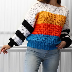 May include: A colorful striped crochet sweater with black and white stripes on the sleeves. The sweater is made in a variety of colors, including white, yellow, orange, and blue.