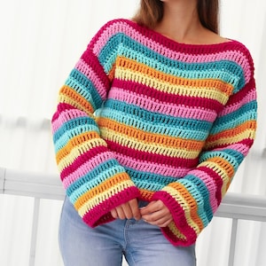 Peut inclure: Un pull en crochet ray&eacute; color&eacute; &agrave; manches longues et &agrave; la coupe ample. Le pull est r&eacute;alis&eacute; avec une vari&eacute;t&eacute; de couleurs vives, dont le rose, le bleu, le jaune et l'orange.