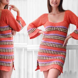 May include: A crochet dress with a colorful striped pattern in shades of orange, brown, white, and purple. The dress has a scoop neck, long sleeves, and a loose fit.