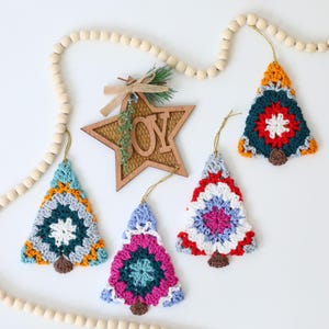 Puede incluir: Cuatro adornos de &aacute;rbol de Navidad de ganchillo en varios colores, incluidos rojo, azul, verde, amarillo y blanco. Los adornos cuelgan de una guirnalda de cuentas de madera con un recorte de estrella de madera que dice "ALEGR&Iacute;A".