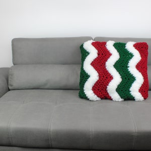 May include: A gray couch with a red, white, and green crocheted pillow with a chevron pattern.