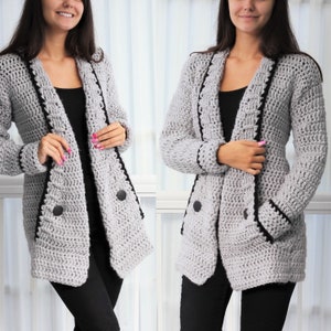 May include: A gray crocheted cardigan with black trim and buttons. The cardigan has a long, open front and a relaxed fit.