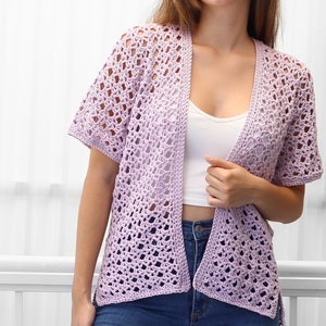 May include: A light purple crochet cardigan with a V-neck and short sleeves. The cardigan is open in the front and has a loose fit.