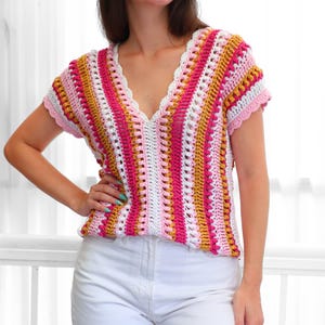 Puede incluir: Un top de crochet de manga corta y cuello en V. Presenta rayas verticales en tonos rosa, blanco y amarillo, y un borde festoneado. La prenda est&aacute; hecha a mano y tiene un corte holgado.