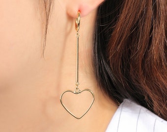 May include: Gold hoop earrings with a long, thin bar and a heart charm dangling from the bottom.