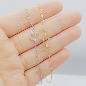 A silver and a gold Aquarius constellation bracelets (left and right).