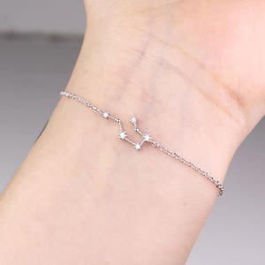 This photo shows the front of a silver Aquarius constellation bracelet.