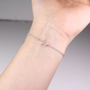 This photo shows the front of a silver Aquarius zodiac bracelet.