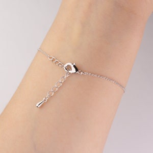 This photo shows the back of a silver Sagittarius astrology bracelet hanging on a woman's wrist.