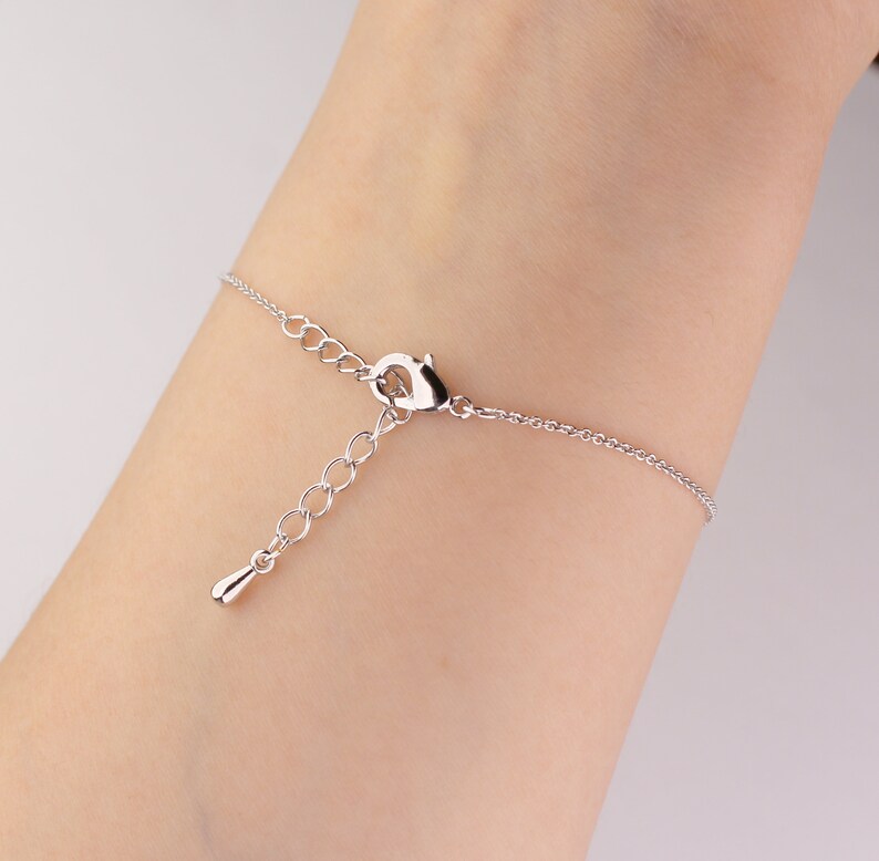 This photo shows the back of a silver Sagittarius astrology bracelet hanging on a woman's wrist.