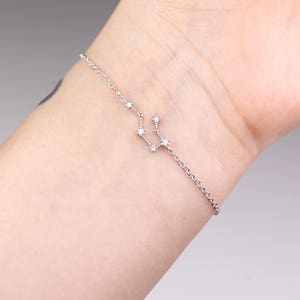 This photo shows the front of a silver Aquarius astrology bracelet.