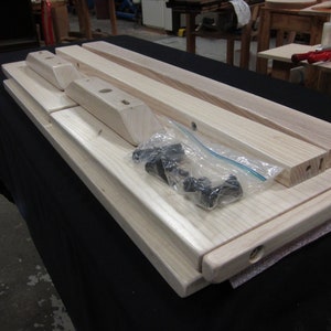 May include: A set of unfinished wooden table legs and top pieces, ready for assembly. The set includes hardware in a clear plastic bag.