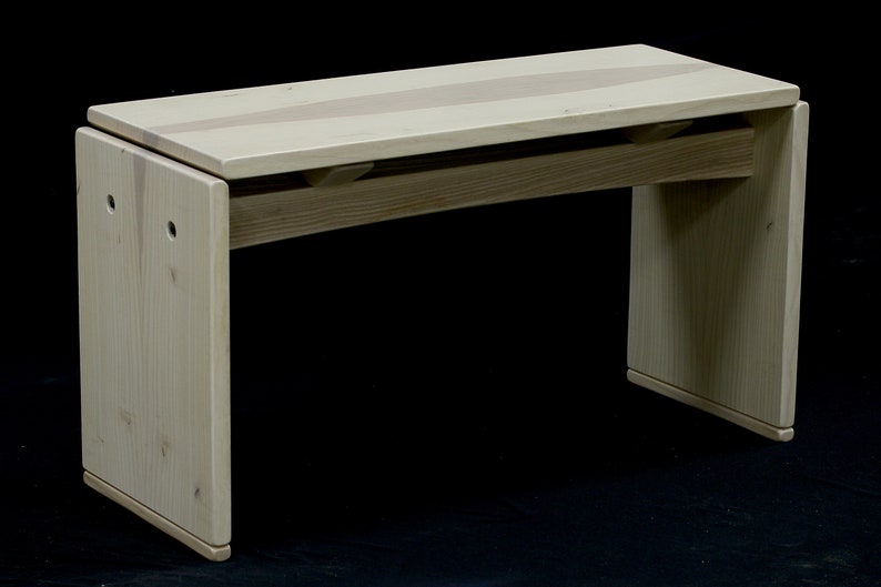 May include: A light wood bench with a curved top and a natural finish. The bench has two legs on each side and is made of solid wood.