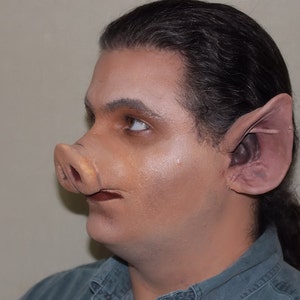 May include: A person wearing a blue shirt with a pig nose and large ears attached to their face.
