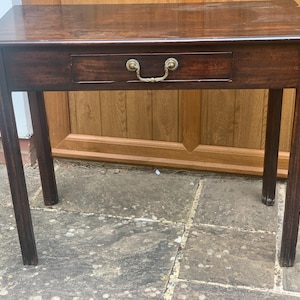 May include: A dark brown wooden side table with a single drawer and brass handle. The table has four slender legs and a rectangular top. The drawer is centered and has a decorative brass pull. The table is approximately 76 cm long.