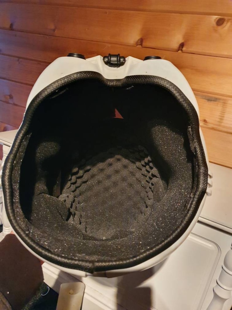 May include: White helmet with a black interior and a black rim. The inside of the helmet has a textured, foam padding. The helmet has two black circular features on the top and a black clasp.