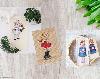 May include: Three cross-stitch embroidery patterns featuring girls in winter clothing. One pattern shows a girl in a white dress holding a bird, another shows a girl in a red dress ice skating, and the last pattern shows two girls in blue dresses holding birds.
