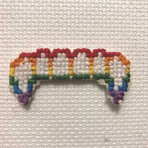Op de afbeelding: Regenboogkleurige kruissteek van een set tanden, een populair symbool van de LGBTQ+-gemeenschap.