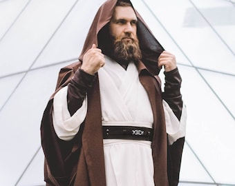 May include: A brown hooded robe with a white undergarment and a black belt. The robe is worn by a person with a long beard.