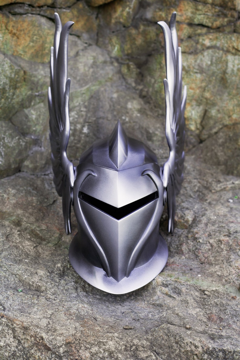 May include: A silver knight helmet with a pointed top and winged accents. The helmet has a face shield with a pointed opening for the eyes.