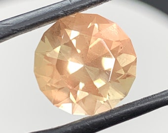 Large peach color Oregon Sunstone. 6.24ct round brilliant gem with light copper Schiller.
