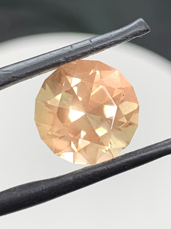 Large peach color Oregon Sunstone. 6.24ct round brilliant gem with light copper Schiller.