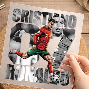 Könnte beinhalten: Ein quadratischer Grafikdruck, der einen Fußballspieler in rotem Trikot und grüner Hose zeigt, der einen Fußball tritt. Im Hintergrund sind eine große Zahl 07 und ein Graustufenporträt des Sportlers zu sehen. Der Text CRISTIANO RONALDO ist fett gedruckt.