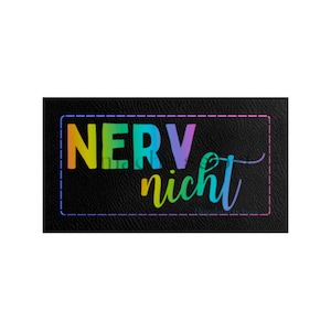 Könnte beinhalten: Ein schwarzer Leder-Patch mit einem regenbogenfarbenen Text, der "NERV nicht" sagt.
