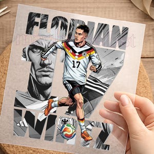 Könnte beinhalten: Transparenter Aufkleber mit einem Fußballspieler in einem weißen, schwarzen und gelben Trikot mit der Nummer 17. Der Aufkleber trägt den Namen "FLORIAN WIRTZ" in großen, stilisierten Buchstaben. Im Hintergrund befindet sich ein Graustufenbild eines Gesichts.