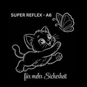 Könnte beinhalten: Ein reflektierender Aufkleber auf schwarzem Hintergrund mit einer Strichzeichnung eines Kätzchens, das nach einem Schmetterling greift. Der Text lautet oben SUPER REFLEX - A6 und unten für mehr Sicherheit in einer weißen Schreibschrift.