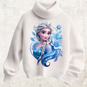 Könnte beinhalten: Weißer Rollkragenpullover mit einem Aufdruck einer Cartoon-Prinzessin mit silbernem Haar, blauen Augen und einem blauen Kleid. Das Design umfasst blaue Blumen und Blätter. Der Pullover ist aus weichem Strickmaterial.