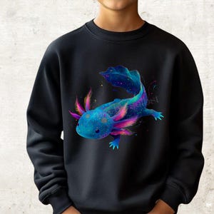 Könnte beinhalten: Schwarzes Sweatshirt mit einer lebendigen Illustration eines Axolotls. Der Axolotl ist in Blau-, Lila- und Rosatönen dargestellt, mit einem gesprenkelten Muster und detaillierten Kiemen. Das Design hat ein kosmische Thema mit kleinen Sternen und farbenfrohen Akzenten.