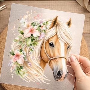 Könnte beinhalten: Aquarell-Illustration eines Pferdekopfes mit fließender, blonden Mähne und geschmückt mit rosa und lila Blumen. Das Pferd hat ein hellbraunes Fell und trägt einen Zaum. Das Kunstwerk befindet sich auf Papier.
